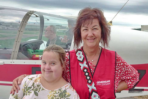 Frau und Mädchen mit Behinderung vor einem Flugzeug. 