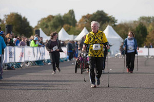 Ein älterer Mann mit Nordic-Walking-Stöcken erreicht das Ziel.