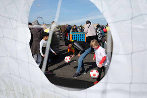 Kinder spielen mit einem Fußball vor einer Torwand. 