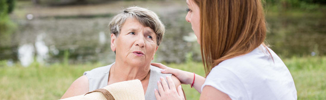 Junge Frau hält eine erschöpfte ältere Frau im Sommer. 