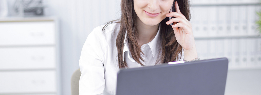 Frau sitzt man einem Laptop und telefoniert