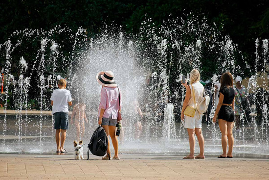 Springbrunnen einer Stadt. Darum Menschen mit sommerlicher Kleidung.