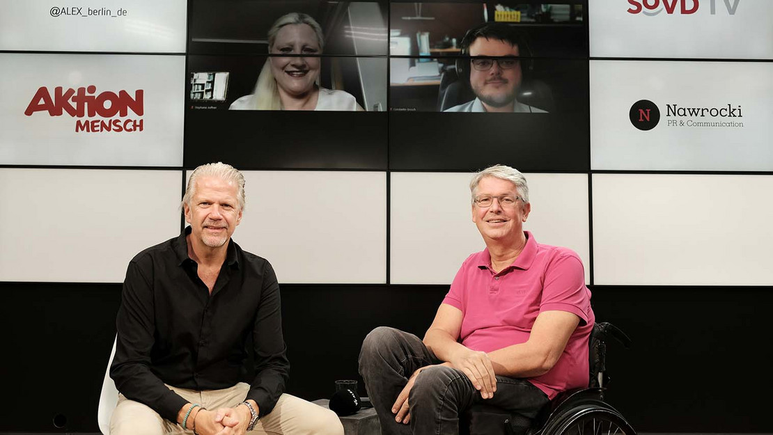 Zwei Menschen im Studio, im Hintergrund zugeschaltete Gäste auf Bildschirmen. 