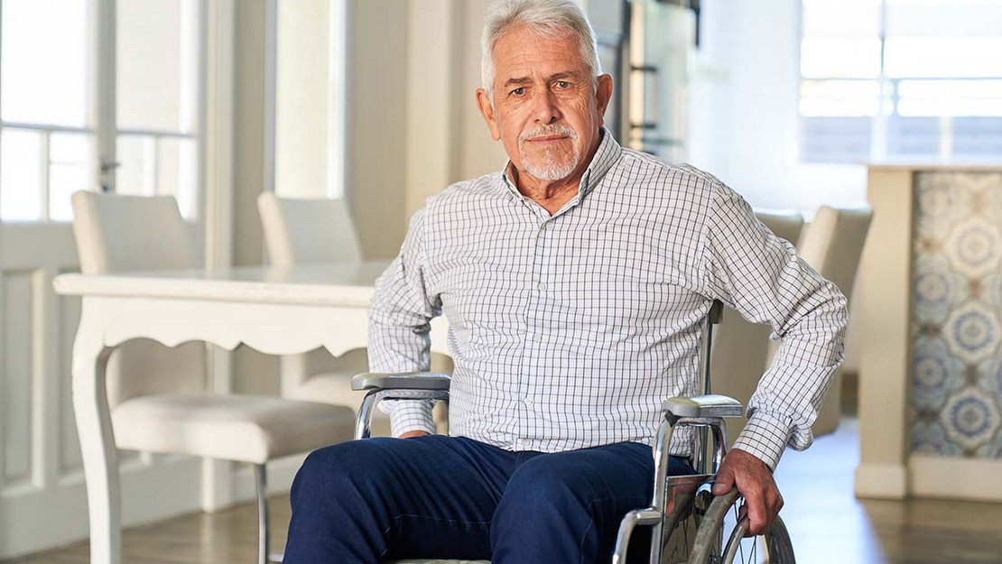Älterer Mann im Rollstuhl in seiner Wohnung. 